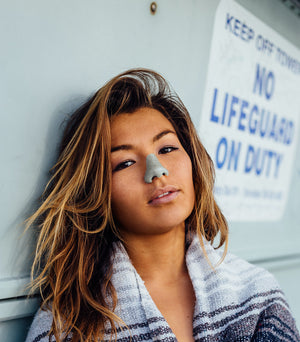 Poolside woman wearing sky blue Noz natural sunscreen on her nose